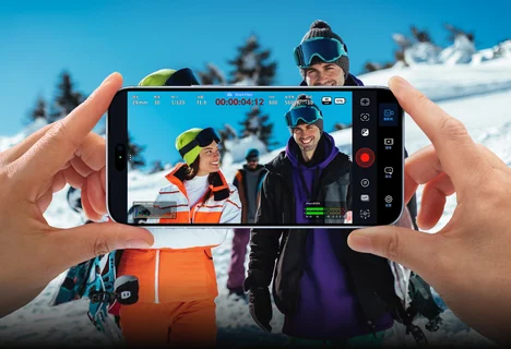 手持手机以 Blackmagic Camera 在雪场拍摄，屏幕显示录制界面